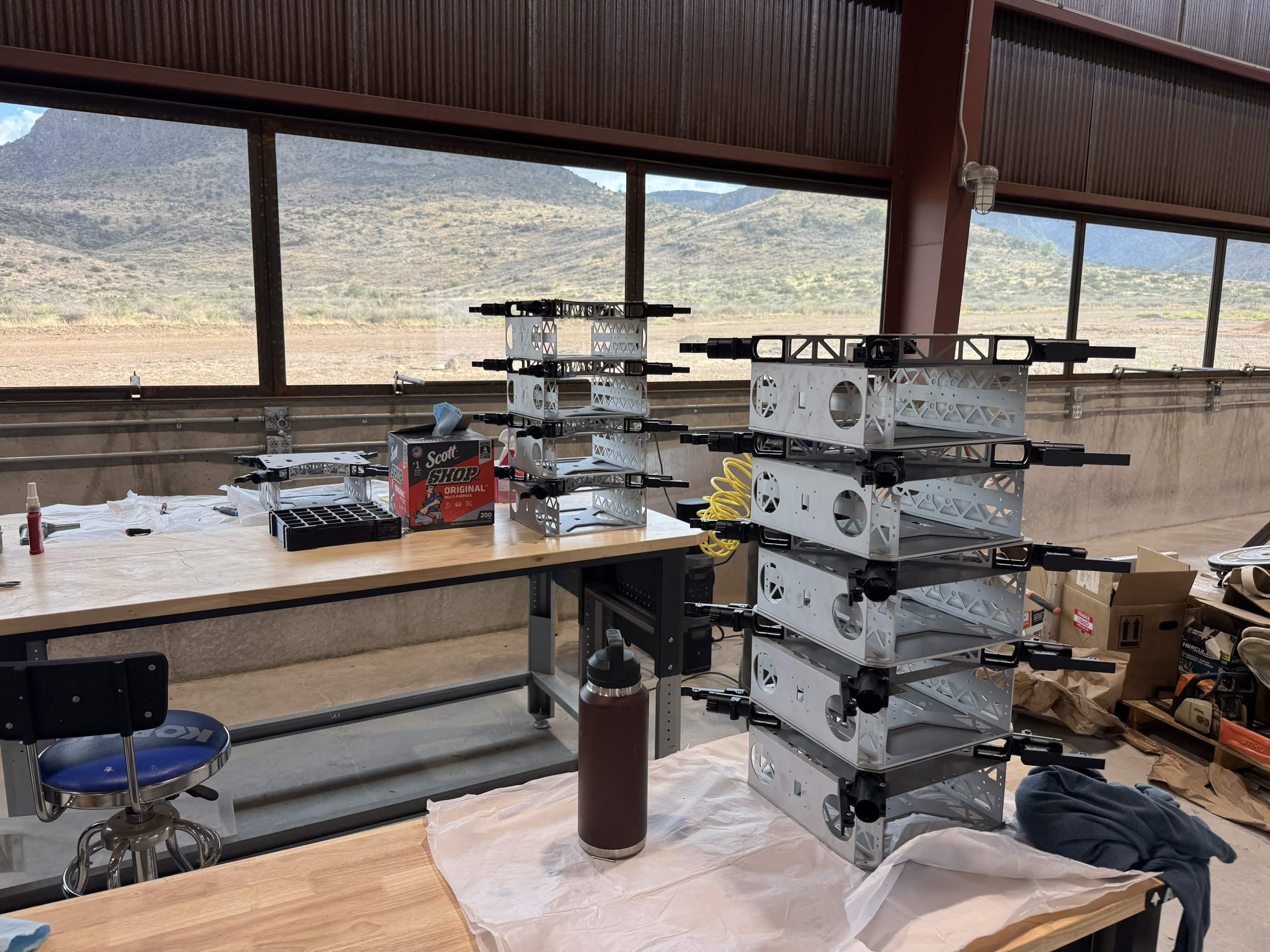 Stack of Quiver airframe chassis on the assembly bench, Davis Mountains through the windows